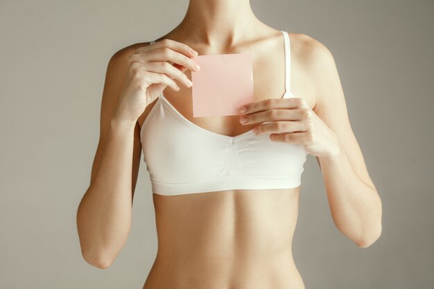 Modelo feminino segurando um post-it rosa vazio