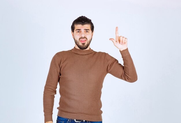 modelo jovem bonito em pé e apontando para cima.