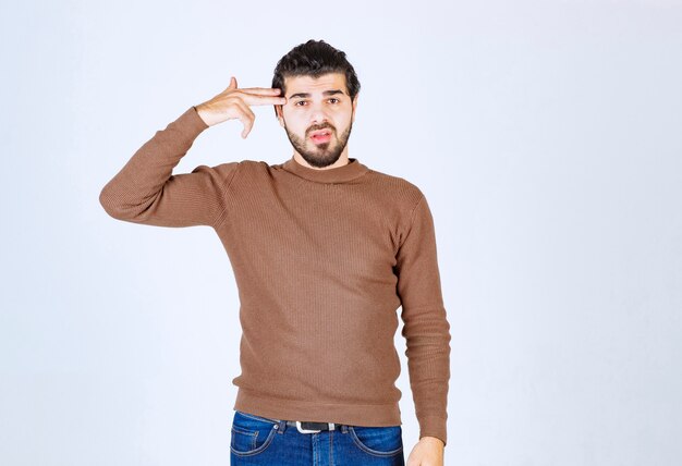 modelo jovem bonito mantendo dois dedos perto da cabeça.