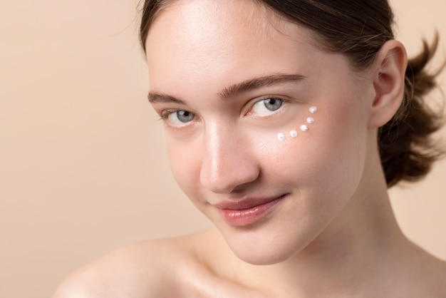 Modelo jovem de alto ângulo usando creme para os olhos