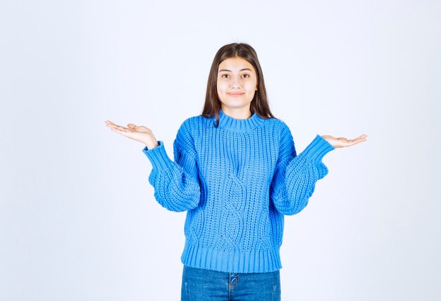 modelo jovem de suéter azul em pé e posando em branco-cinza.