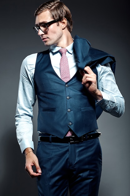 Modelo masculino jovem empresário bonito elegante de terno azul e óculos da moda, posando no estúdio