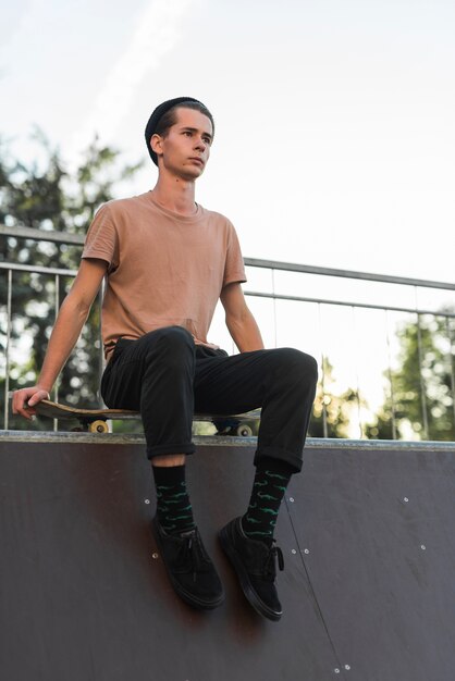 Modelo masculino jovem sentado no skate