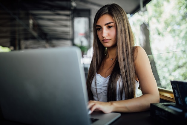 Foto grátis modelo muito sorridente trabalhando em seu laptop no terraço do café daytilme