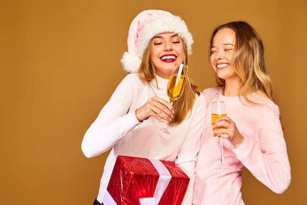 Modelos com grande caixa de presente bebendo champanhe em copos comemorando o ano novo