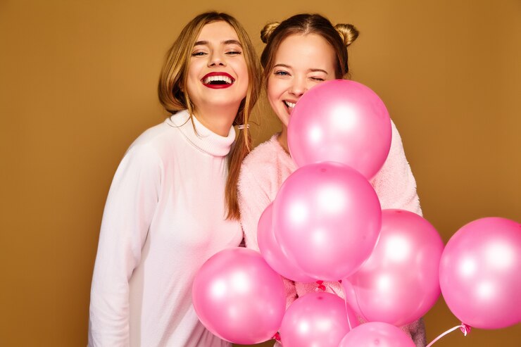 Foto grátis modelos de mulheres com balões de ar rosa na parede dourada