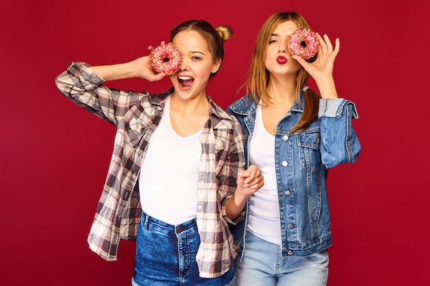 Modelos femininos segurando rosquinhas rosa com granulado