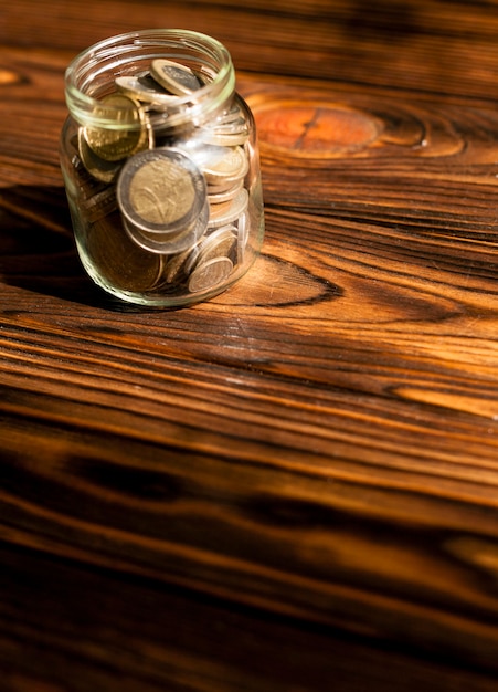 Foto grátis moedas de alta vista em uma jarra com fundo de madeira