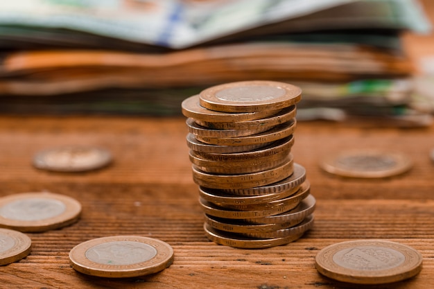 Moedas, notas na mesa de madeira.