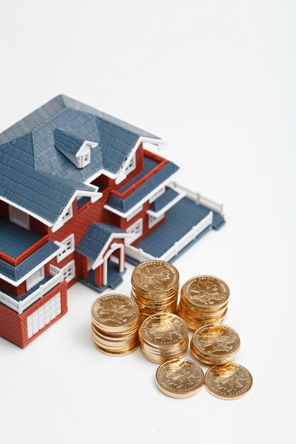 Moedas RMB empilhadas em frente ao modelo habitacional (preços das casas, compra de casas, imóveis, conceito de hipoteca)