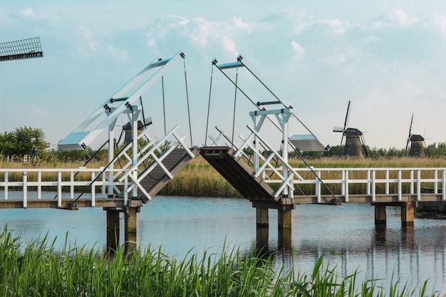 Moinhos holandeses tradicionais bonitos perto de canais de água com ponte levadiça