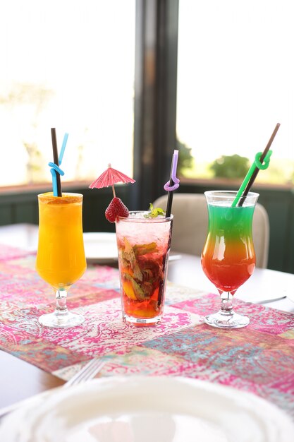 Mojito de morango com suco de laranja e coquetel colorido em cima da mesa