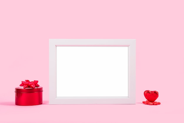 Moldura para fotos entre caixa de presente vermelha e coração de ornamento