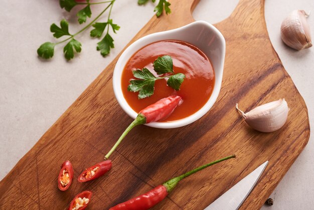 Molho de pimenta vermelha. ketchup de tomate, molho de pimenta, purê com pimenta, tomate e alho. na tábua de madeira na superfície da pedra. vista do topo.