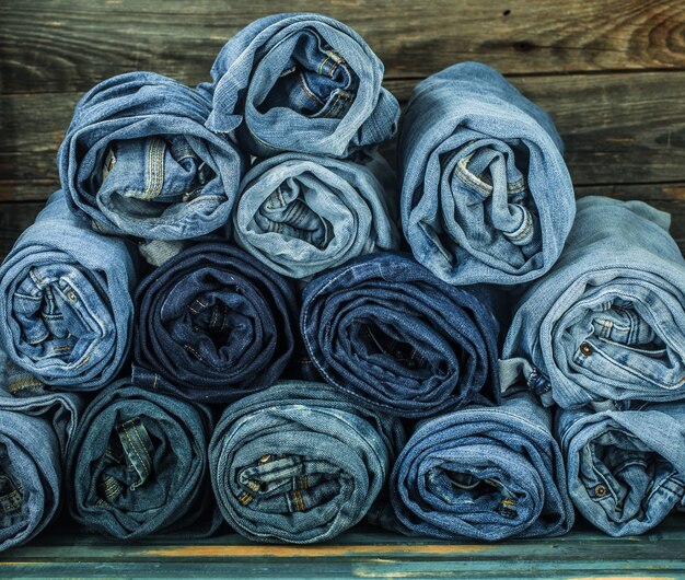 monte de jeans torcidos em uma parede de madeira, roupas da moda