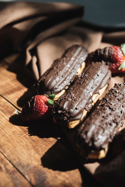 Morango com chocolate éclairs na mesa de madeira na luz solar