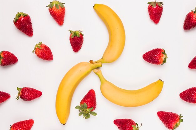 Morango vermelha brilhante e banana amarela no fundo branco