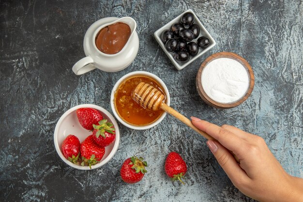 Morangos frescos com mel e azeitonas na superfície escura de gelatina de frutas frescas