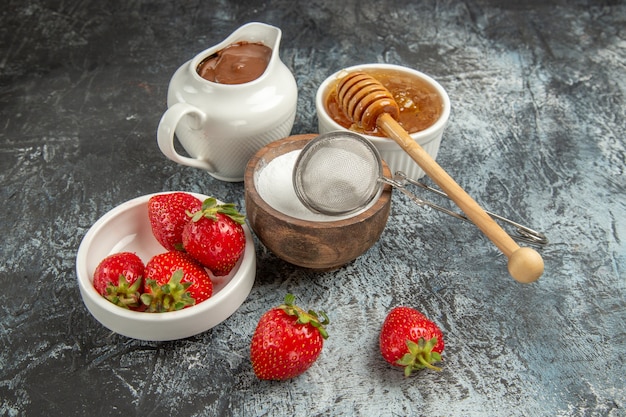 Morangos frescos com mel na superfície escura de frutas e frutas vermelhas doces de frente