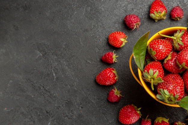 Morangos frescos vermelhos alinhados em mesa com frutas vermelhas frescas