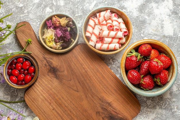 Morangos frescos vermelhos com flores na superfície branca de frutas vermelhas doces de frutas vermelhas