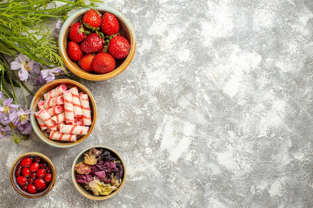 Morangos frescos vermelhos com flores na superfície branca de frutas vermelhas doces