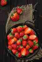 Foto grátis morangos maduros em um prato de metal em um fundo de madeira velho com espaço de cópia ponto de vista de cima do quadro vertical deliciosa sobremesa natural comida sazonal