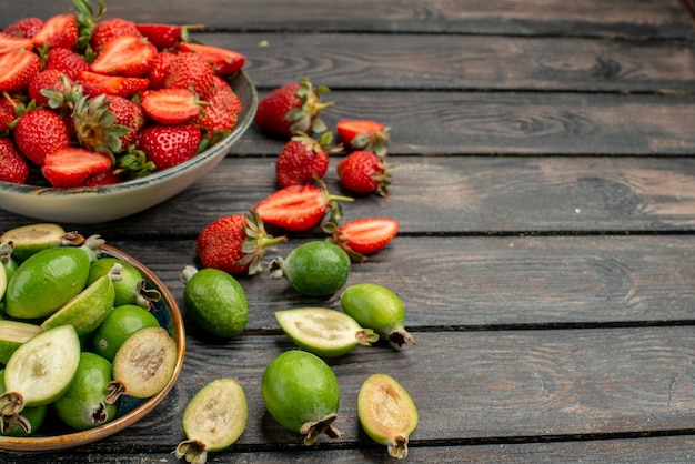 Morangos vermelhos com feijoas frescas na mesa de madeira escura rústica cor de verão suco de árvore baga selvagem