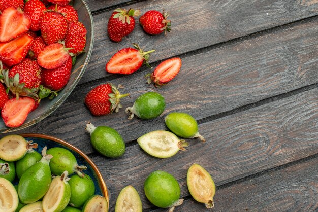 Morangos vermelhos com feijoas frescas na mesa de madeira escura