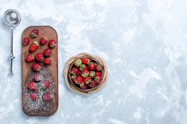 Morangos vermelhos de cima com frutas frescas e suaves em uma mesa branca