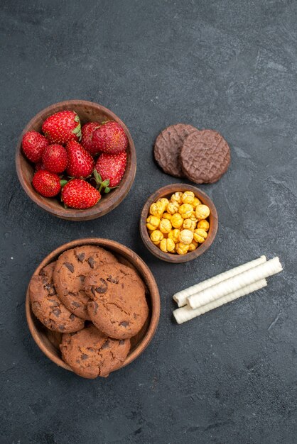 Morangos vermelhos frescos com biscoitos doces em um bolo de biscoito de açúcar de mesa escura de vista superior