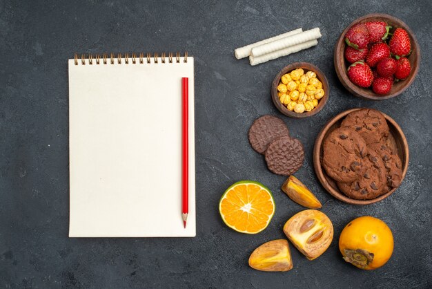 Morangos vermelhos frescos com biscoitos na mesa escura.