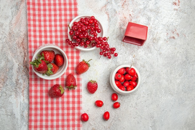 Morangos vermelhos frescos com frutas em uma mesa branca