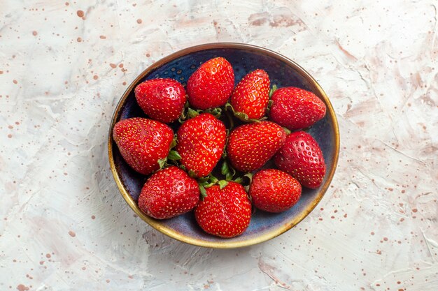 Morangos vermelhos frescos de vista de cima dentro do prato na mesa branca com frutas vermelhas frescas