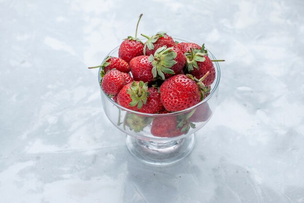 morangos vermelhos frescos e frutas suaves de verão dentro de um prato de vidro na mesa branca