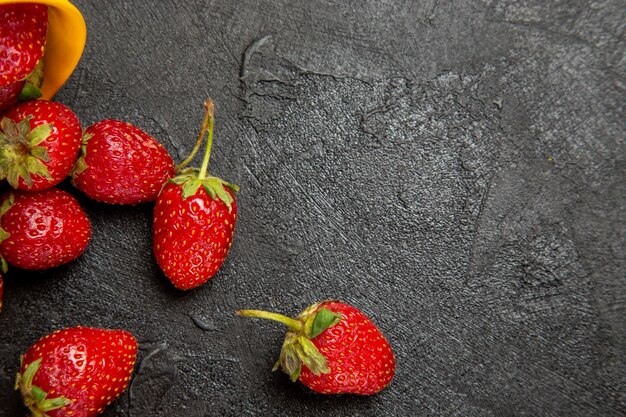 Morangos vermelhos frescos em piso escuro com frutas vermelhas maduras