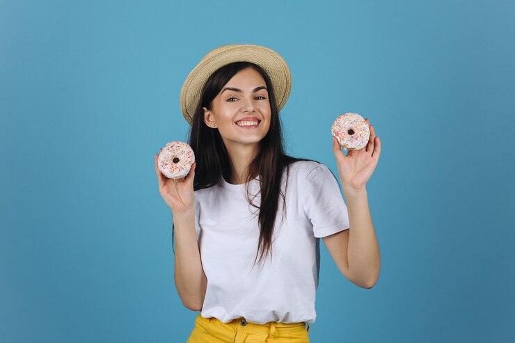 Foto grátis morena alegre se diverte posando com deliciosos donuts no estúdio