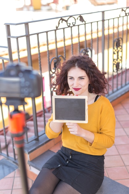 Morena blogueiro mostrando o quadro-negro para a câmera