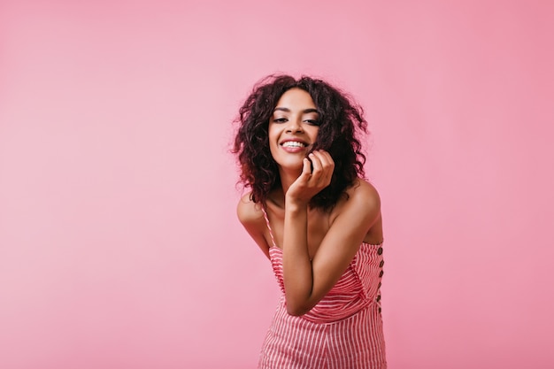 Foto grátis morena brilhante, estilosa e positiva com cachos posando com ousadia e com um sorriso. retrato de uma linda mulher africana com roupas da moda.