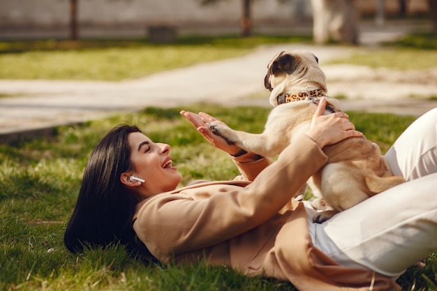 Morena com um casaco marrom caminha com pug