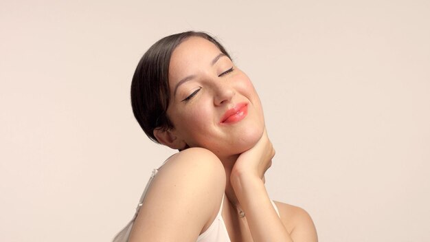 Morena de beleza com modelo de corte de cabelo curto em estúdio sozinho com pele brilhante ideal com olhos fechados e totalmente feliz