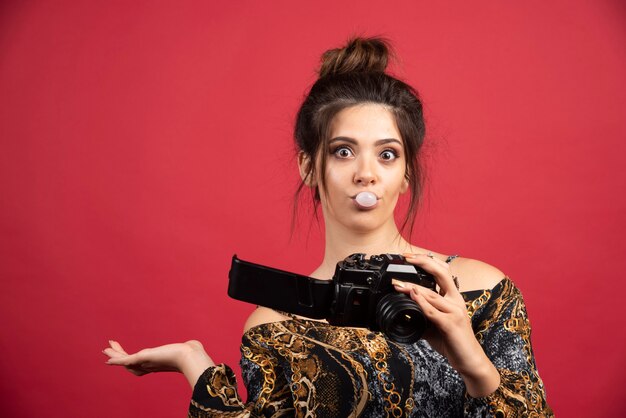 Morena fotografia menina mascando chiclete e verificando o histórico da foto.