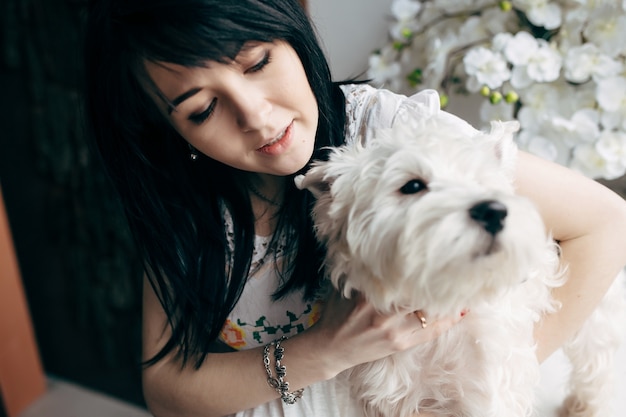 Morena jovem com cachorro encantador em casa