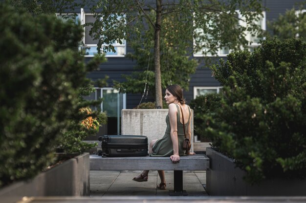 Morena mulher sentada no assento de cimento no parque urbano