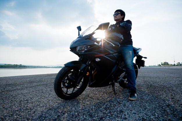Motorbiker bonito com capacete nas mãos da motocicleta