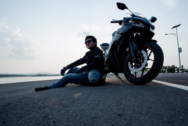 Motorbiker bonito com capacete nas mãos da motocicleta