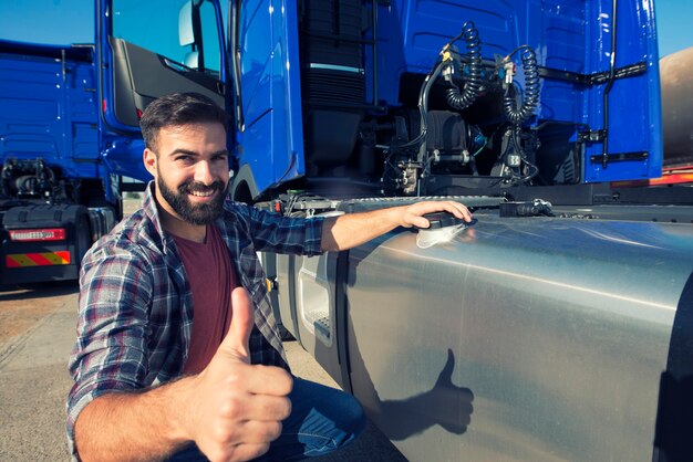 Motorista de caminhão abrindo tanque reservatório para reabastecer o caminhão e segurando o polegar para cima