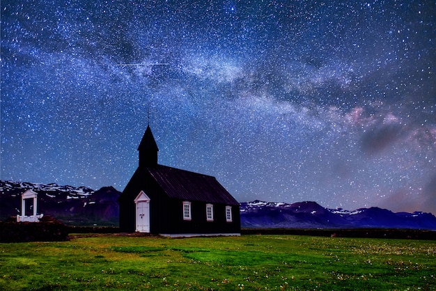 Mountain view islândia. céu estrelado fantástico e a via láctea. bela igreja de madeira preta em budir