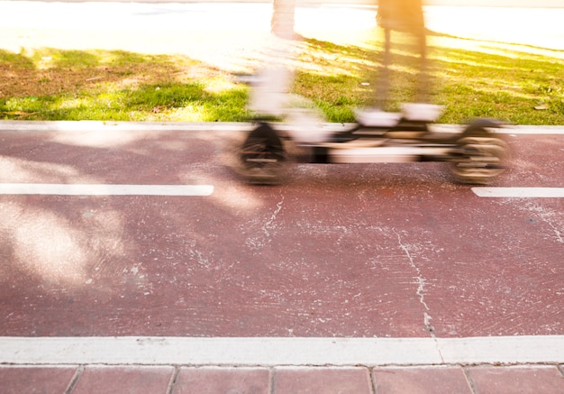 Movimento desfocado de uma pessoa andando de scooter em um parque da cidade