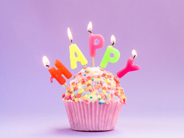 Muffin de aniversário delicioso com velas coloridas
